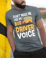 Don’t Make Me Use My Bus Driver Voice T-Shirt for Adults - model in grey shirt leaning against column