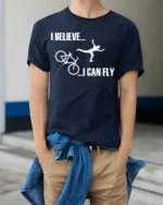 I Believe I Can Fly Funny Bike Crash T-Shirt for Cyclists - model wearing navy shirt, hands in pockets