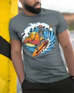 Skeleton Surfing Sunset T-shirt with Beach and Wave Art - model in grey shirt leaning against column