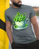 Lucky Shamrock Cup T-Shirt for St. Patrick’s Day Cheer - model in grey shirt leaning against column