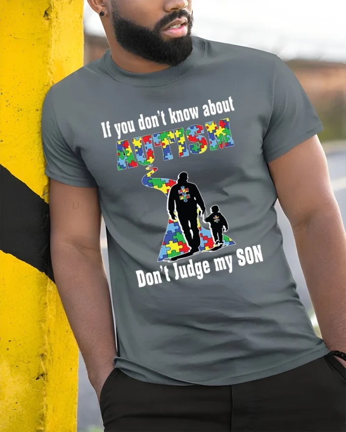 Autism Awareness T-Shirt  Don’t Judge My Son Message - model in grey shirt leaning against column