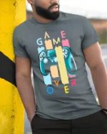 Game Over Controller T-Shirt Funny Gamer Graphic Tee - model in grey shirt leaning against column