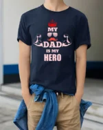 My Dad Is My Hero T-Shirt Funny Father’s Day Gift - model wearing navy shirt, hands in pockets