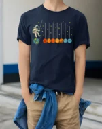 Astronaut Swinging on Planets Funny Space T-Shirt for Adults - model wearing navy shirt, hands in pockets