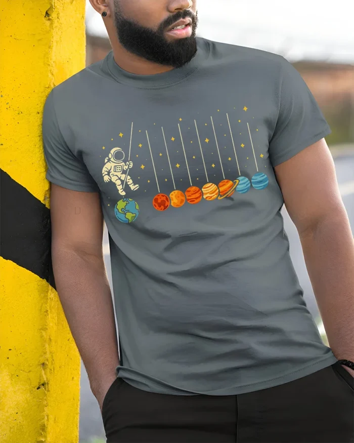 Astronaut Swinging on Planets Funny Space T-Shirt for Adults - model in grey shirt leaning against column