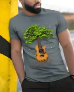 Tree Guitar Nature Music Graphic T-Shirt for Music Lovers - model in grey shirt leaning against column
