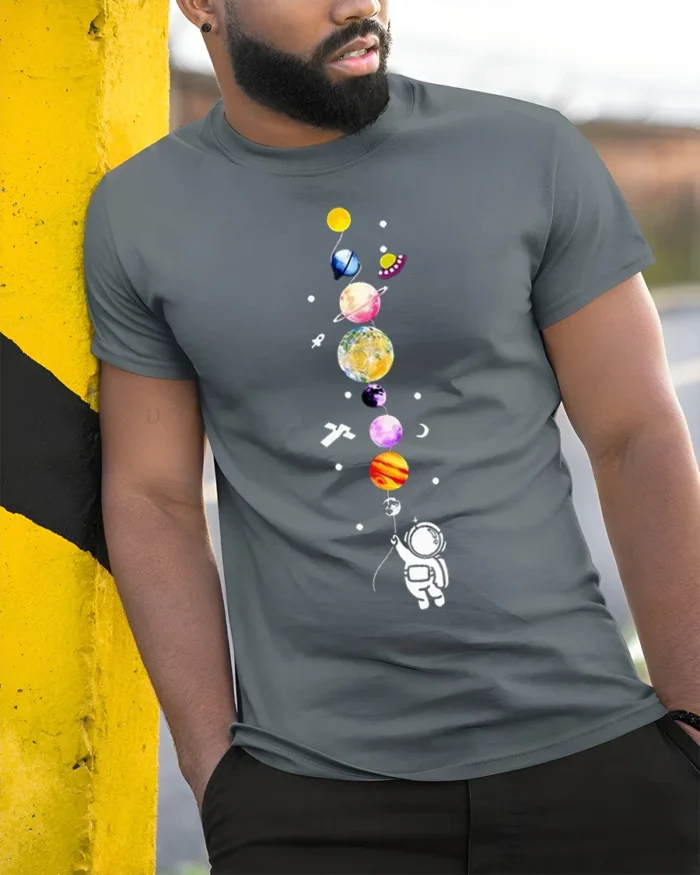 Cute Astronaut Holding Planets Balloon Galaxy T-Shirt - model in grey shirt leaning against column