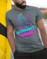 Praying Hands Faith Power Graphic T-shirt - model in grey shirt leaning against column