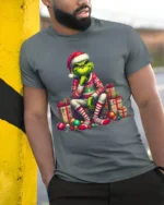 Grumpy Green Santa Christmas Gifts Funny Graphic Tshirt - model in grey shirt leaning against column