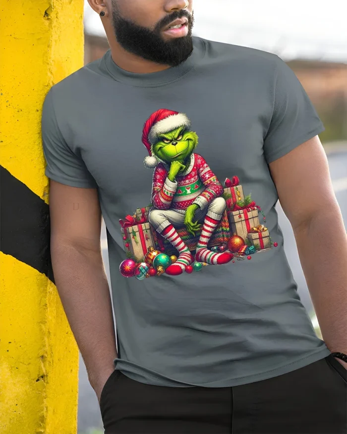 Grumpy Green Santa Christmas Gifts Funny Graphic Tshirt - model in grey shirt leaning against column