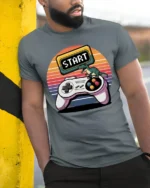 Retro Start Button Gamer Controller T Shirt - model wearing grey tee, leaning on column