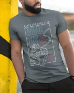 Game On Never Say Game Over Gamer Controller Graphic T Shirt - model wearing grey tee, leaning on column