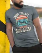 Sorry Im Late I Was On A Side Quest Funny Gamer Graphic T Shirt - model wearing grey tee, leaning on column