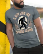 A Guy Like Me Is Hard To Find Funny Bigfoot Sasquatch T Shirt - model wearing grey tee, leaning on column