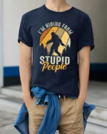 Funny Bigfoot Im Hiding From Stupid People Vintage T Shirt - model wearing navy tee with hands in pockets