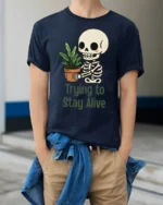 Funny Trying To Stay Alive Skeleton Plant Graphic T Shirt - model wearing navy tee with hands in pockets