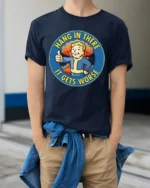 Hang In There It Gets Worse Funny Fallout Style Meme Graphic T Shirt - model wearing navy tee with hands in pockets