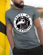 Trust Me Im A Doctor Plague Mask Funny Halloween Graphic T Shirt - model wearing grey tee, leaning on column