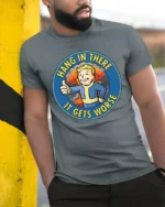 Hang In There It Gets Worse Funny Fallout Style Meme Graphic T Shirt - model wearing grey tee, leaning on column