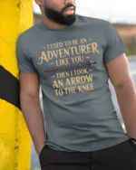 Funny I Used To Be An Adventurer Arrow Knee T Shirt - model wearing grey tee, leaning on column