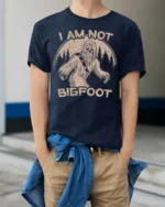 Funny I Am Not Bigfoot Sasquatch Vintage Graphic T Shirt - model wearing navy tee with hands in pockets