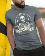 Funny It Is What It Is Skeleton Vintage Graphic T Shirt - model wearing grey tee, leaning on column