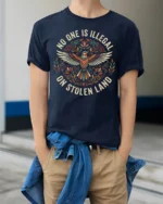 No One Is Illegal On Stolen Land Bold Statement Graphic T Shirt - model wearing navy tee with hands in pockets