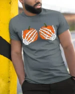 Funny Skeleton Hands Holding Pumpkins Halloween Spooky Graphic T Shirt - model wearing grey tee, leaning on column