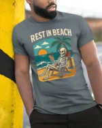 Rest In Beach Funny Skeleton Vacation Graphic Tee Tshirt - model wearing grey tee, leaning on column