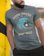 Good Waves Stay Wild Graphic Tee Retro Surf Beach Tshirt - model wearing grey tee, leaning on column