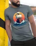 Vintage Sailing Ship Sunset Ocean Graphic Tshirt Adventure Style - model wearing grey tee, leaning on column