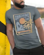 Sunshine And Surf Retro Beach Graphic Tshirt Summer Vibes Style - model wearing grey tee, leaning on column