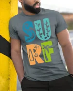 Colorful Surf Typography Beach Summer Retro Graphic Tee - model wearing grey tee, leaning on column