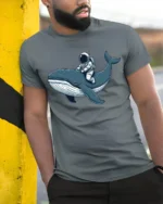 Astronaut Riding Whale Space Ocean Adventure Graphic Tee Tshirt - model wearing grey tee, leaning on column