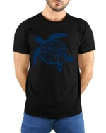 The Ocean Is Magic Sea Turtle Graphic Tee Coastal Style - model wearing black tee with hands behind back