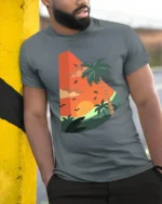 Tropical Sunset Palm Tree Graphic Tee Retro Summer Vibe - model wearing grey tee, leaning on column