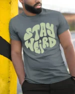 Stay Weird Retro Typography Graphic Tee Vintage Style Vibe - model wearing grey tee, leaning on column