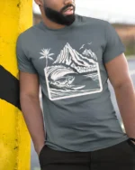 Surfing Iguana Mountain Wave Graphic Tee Tropical Adventure - model wearing grey tee, leaning on column