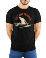 Just Keep Swimming Shark Graphic Tee Funny Ocean Style - model wearing black tee with hands behind back