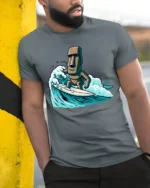 Funny Surfing Moai Statue Graphic Tee Retro Beach Humor Style - model wearing grey tee, leaning on column