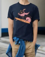 Surfing Flamingo Surfs Up Beach Vibes Funny Graphic Tee - model wearing navy tee with hands in pockets