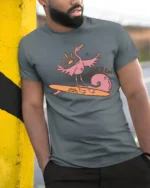 Surfing Flamingo Surfs Up Beach Vibes Funny Graphic Tee - model wearing grey tee, leaning on column
