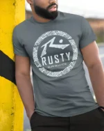 Rusty Surfboards Retro Surf Logo Beach Vibe Graphic Tee Tshirt - model wearing grey tee, leaning on column