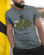Funny Cat Riding Dinosaur Cute Cartoon Graphic Tee Tshirt - model wearing grey tee, leaning on column