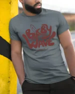 Baby Wave Club Surf Graphic T Shirt Retro Beach Vibe Tee - model wearing grey tee, leaning on column