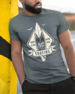 Surfing Surf Club Vintage Style Wave Rider Graphic T Shirt - model wearing grey tee, leaning on column