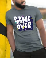 Game Over Funny Retro Gaming Typography Graphic T Shirt - model wearing grey tee, leaning on column