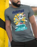 Chill Surfing Goat Retro Sunset Waves Graphic Tshirt - model wearing grey tee, leaning on column