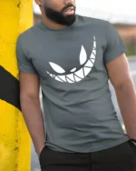 Grinning Cheshire Monster Toothy Smile Graphic Tshirt - model wearing grey tee, leaning on column