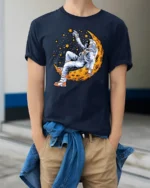 Celestial Dreamer Astronaut Reclining On Moon Graphic Tshirt - model wearing navy tee with hands in pockets